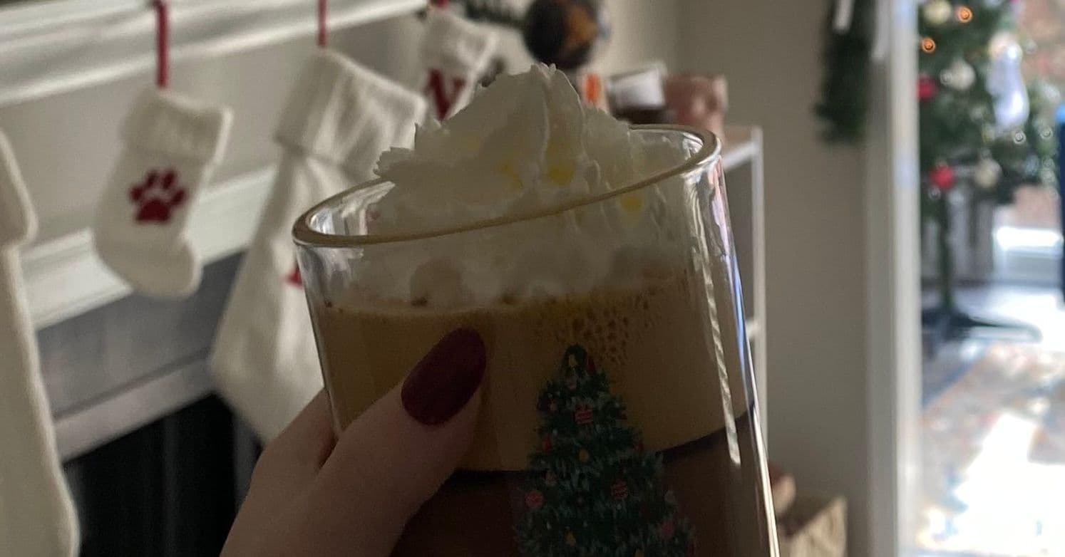 Cup of hot chocolate topped with whipped cream with a Christmas background