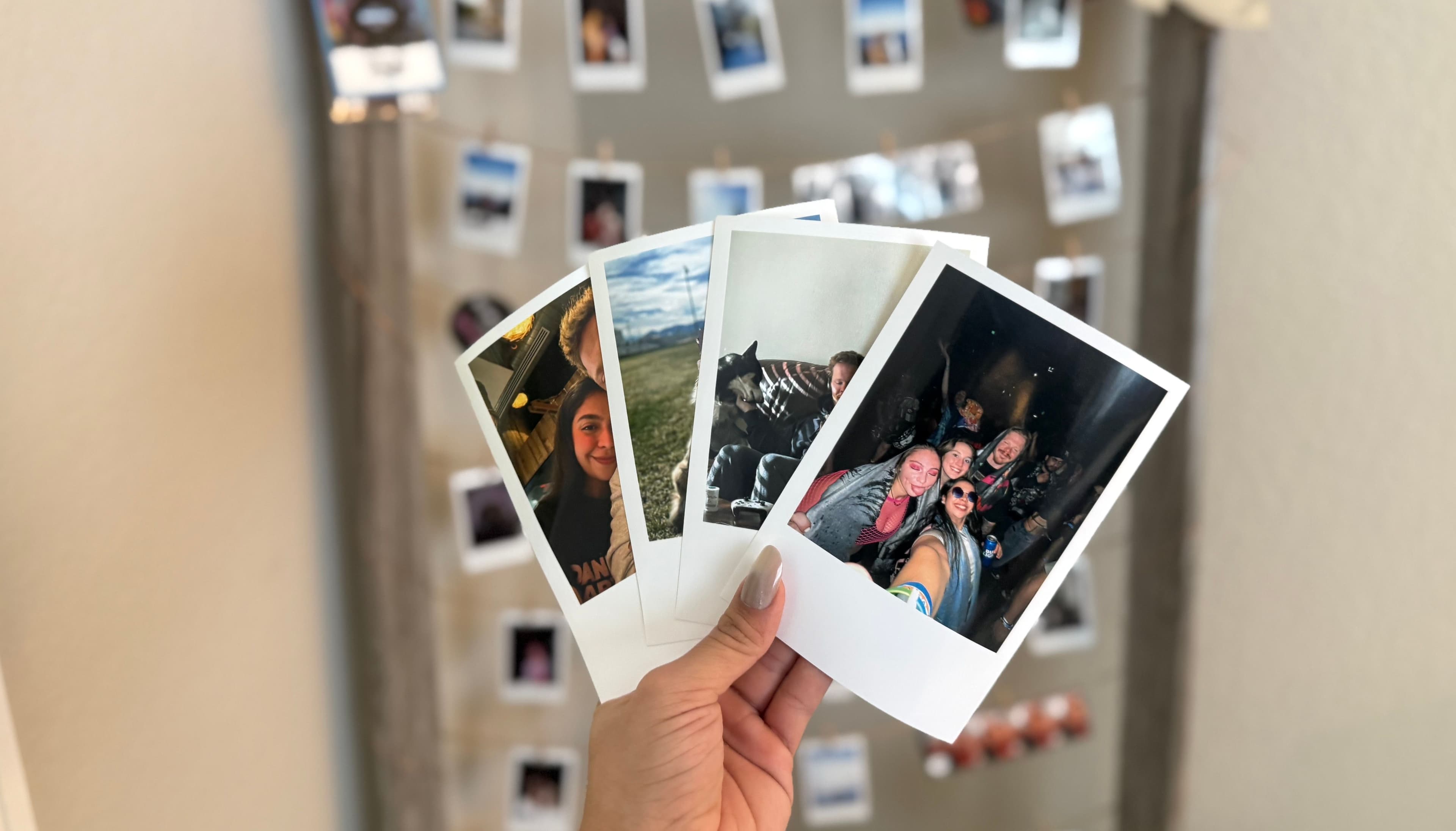 Hands holding retro prints in front of a wall of retro prints