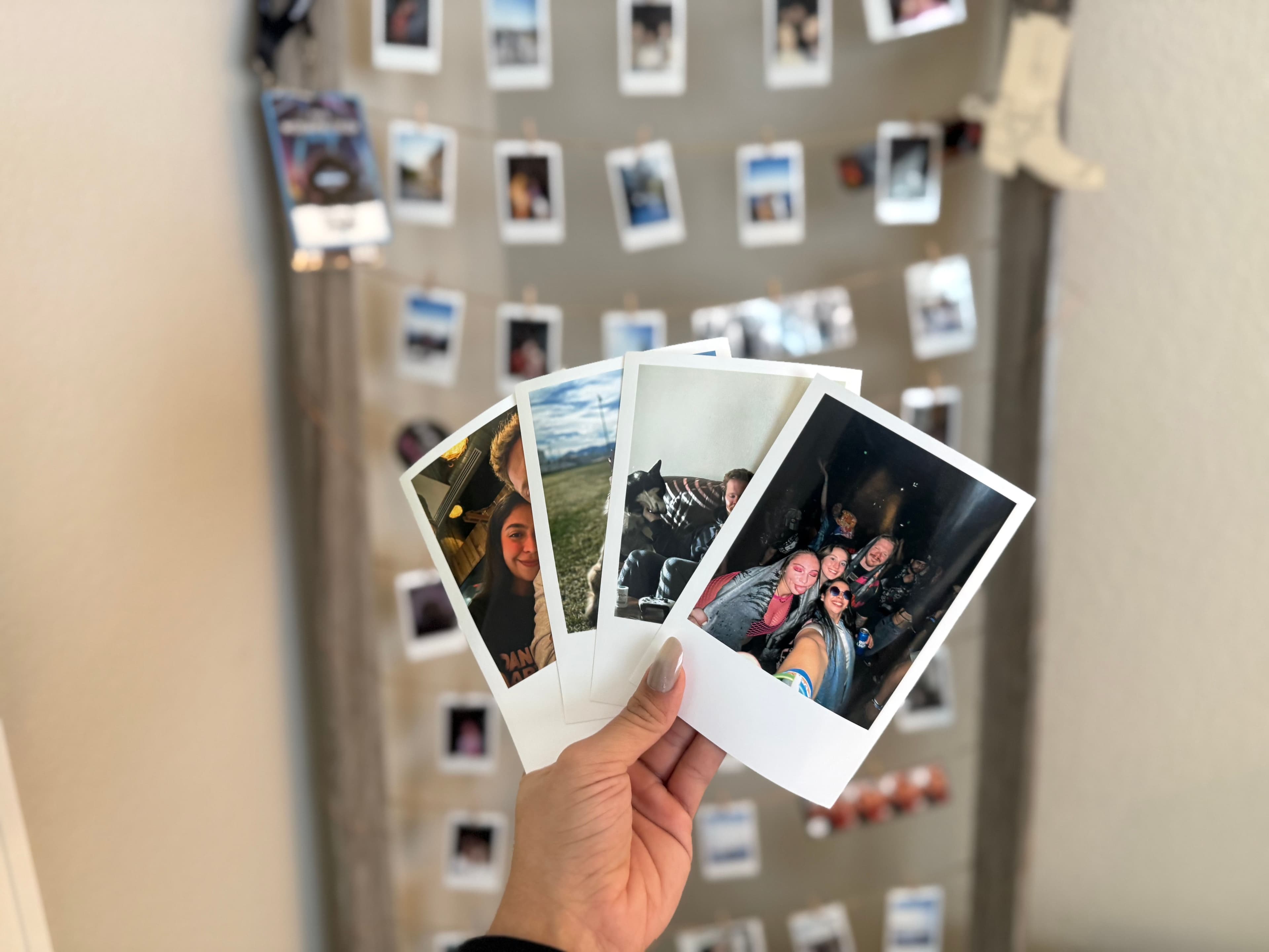 Hands holding retro prints in front of a wall of retro prints