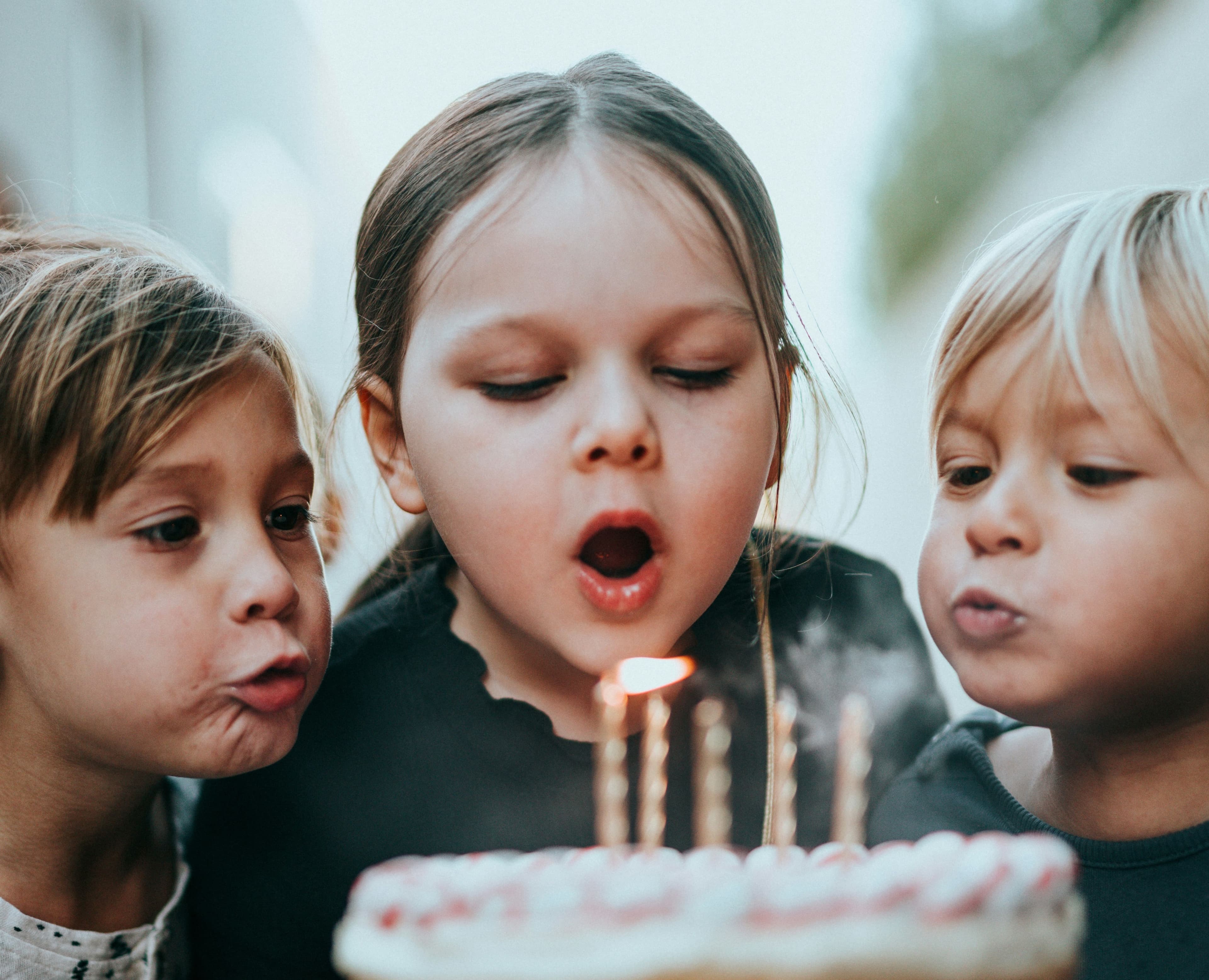 Three kids blowing a candle