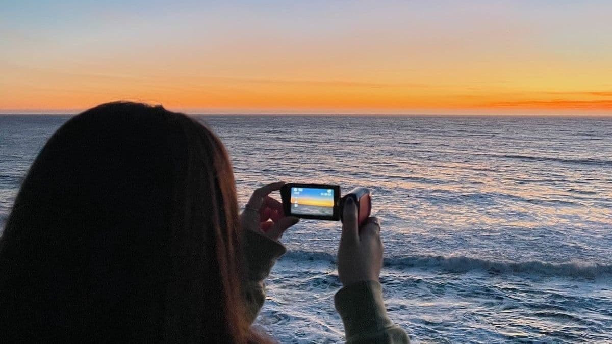 girl taking a photo of sunset