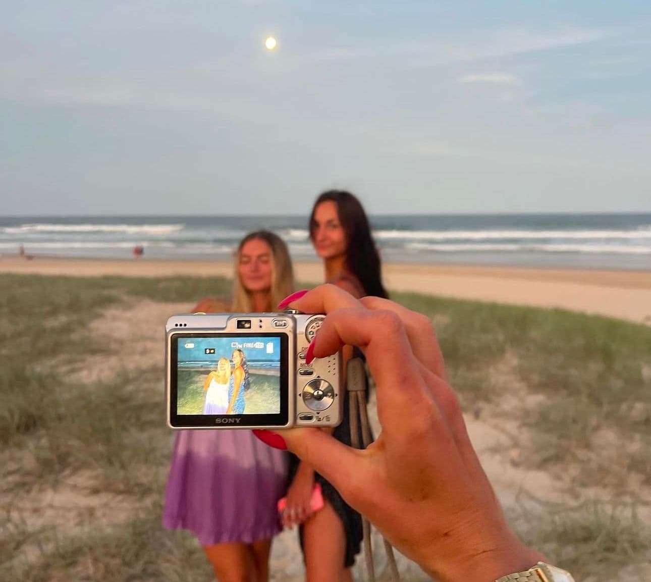 two girls taking a photo with a digital camera