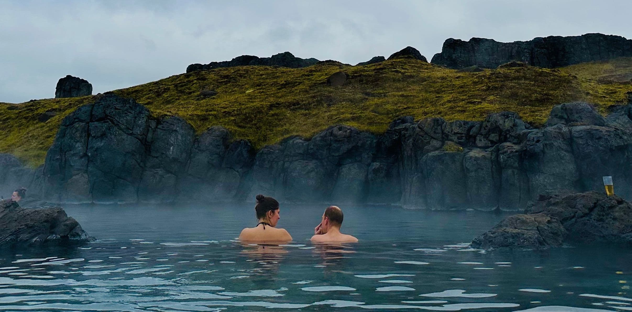 Couple in steaming water with a mountain background