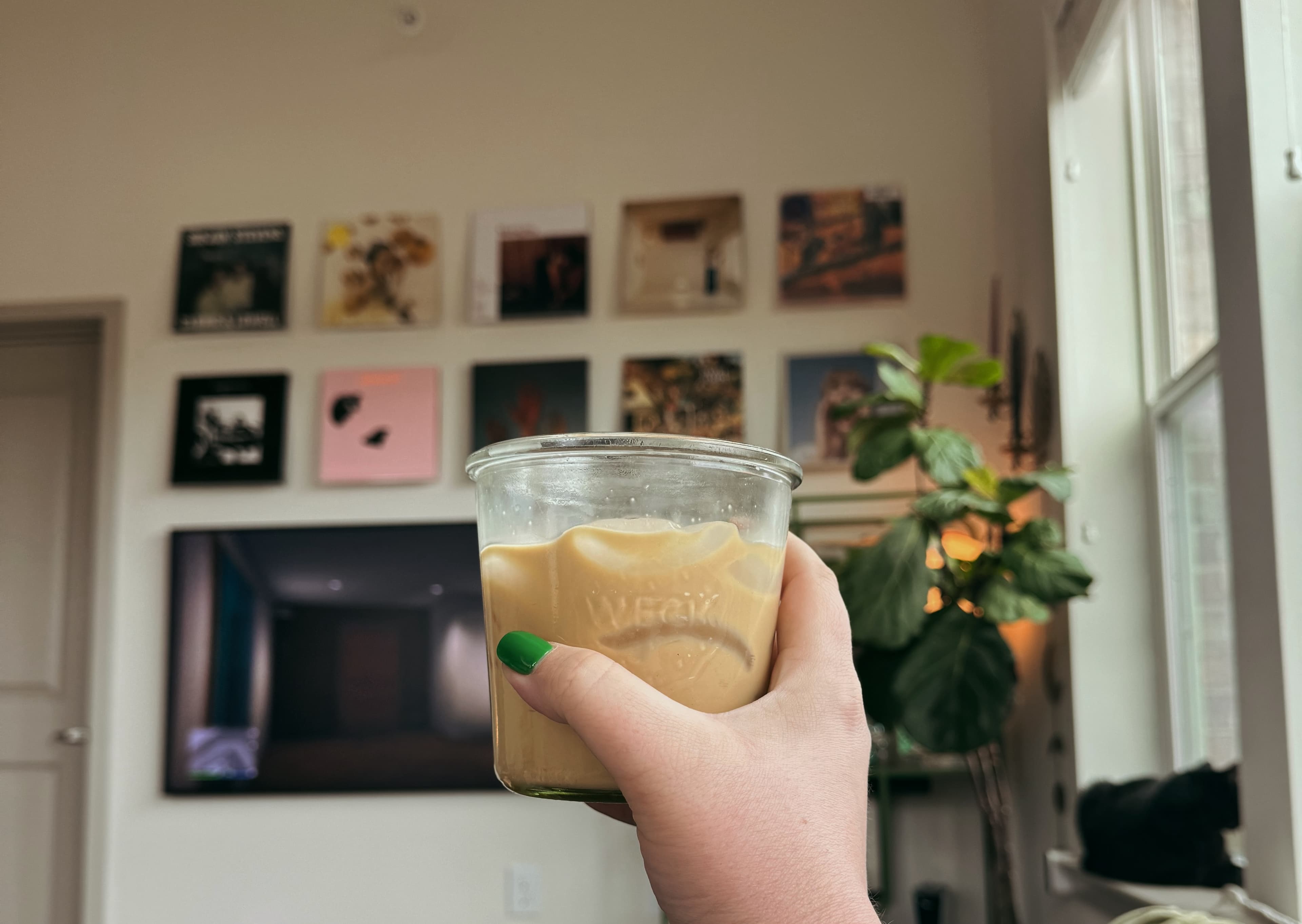 girl holding coffee in front of wall of prints